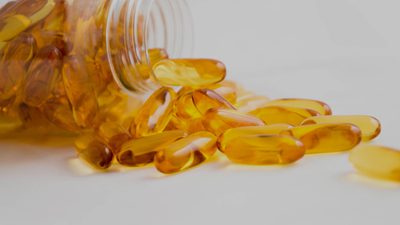 Golden omega-3 capsules spilling from a clear jar
