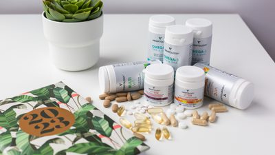 Vegetology supplement range with loose capsules, a notebook and a succulent on a white desk