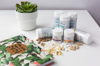 Vegetology supplement range with loose capsules, a notebook and a succulent on a white desk
