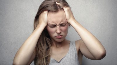 A woman holding her head, illustrating an article on migraines and vitamin D deficiency