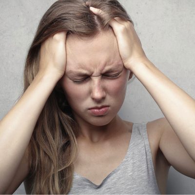 A woman holding her head, illustrating an article on migraines and vitamin D deficiency
