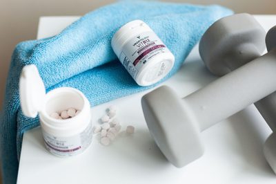 Two Vegetology B12 tubs with loose tablets, a towel and a dumbbell