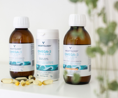 Vegetology Omega-3 Liquid bottles either side of the capsule bottle, with loose capsules and eucalyptus