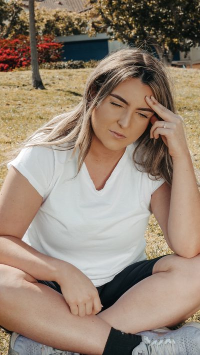 A woman sitting outdoors resting her head on her hand